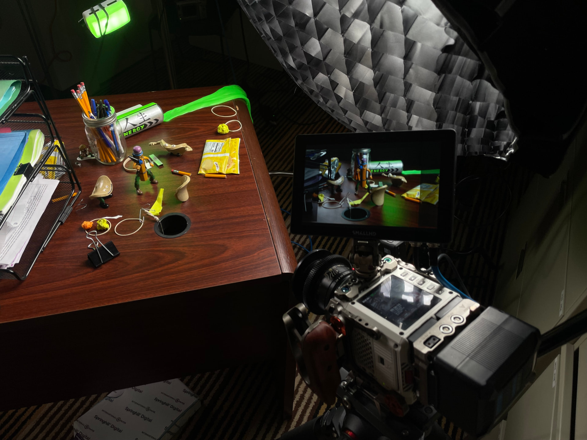 Camera monitor framing a 9 to 5 Warriors figure on a desk with a Jinsei energy can