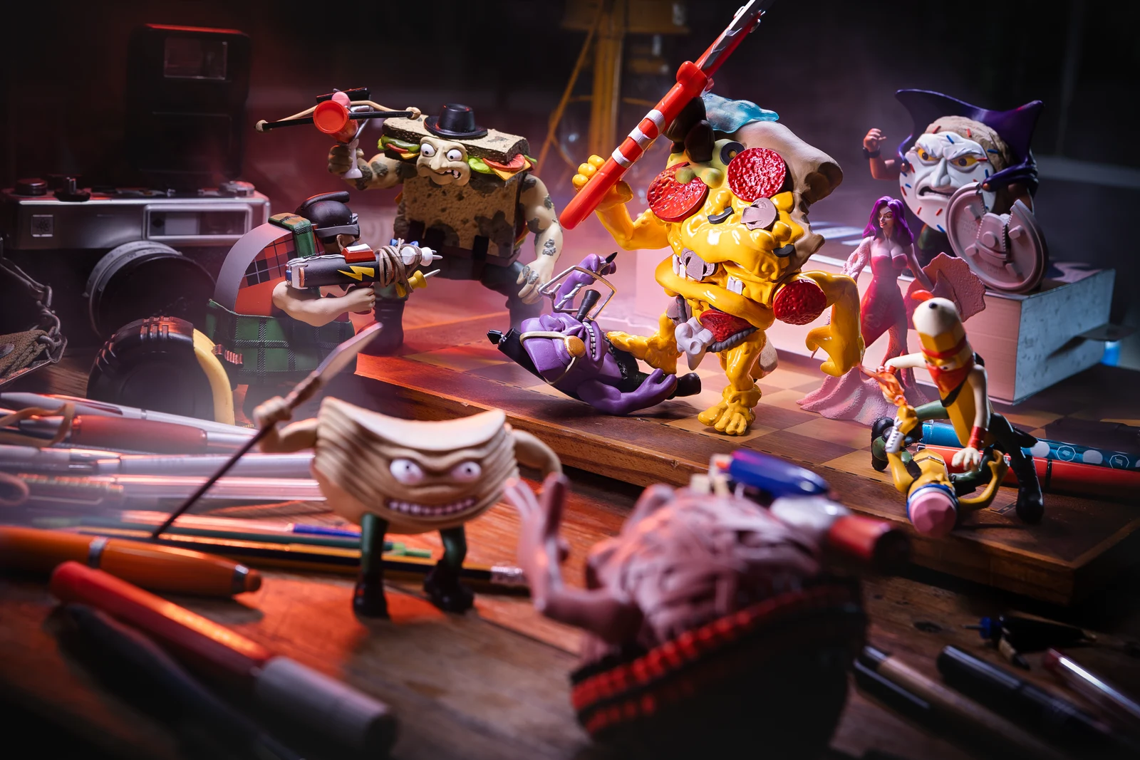 9 to 5 Warriors action figures battle across a desk surrounded by pencils, books and a camera.